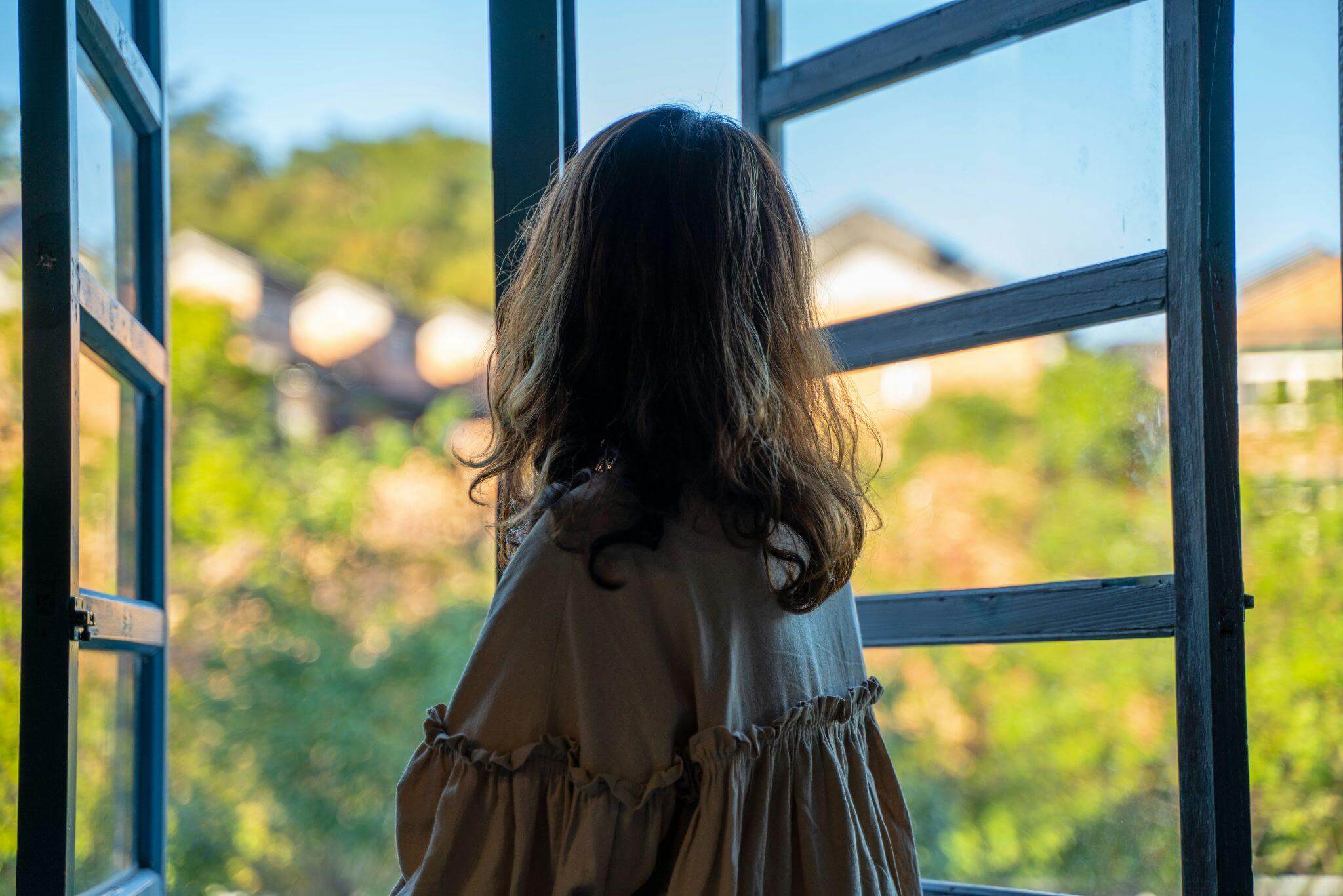 Feeling Guilty for Doing "Nothing" This Summer? An ADHD and Attachment Perspective Person looking out an open window, reflecting on rest, self-compassion, and emotional healing from an ADHD and attachment perspective.